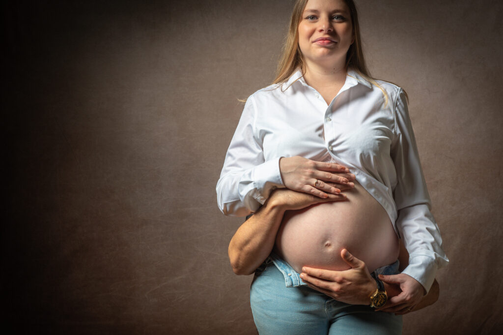 Future maman en chemise blanche, mains sur le ventre