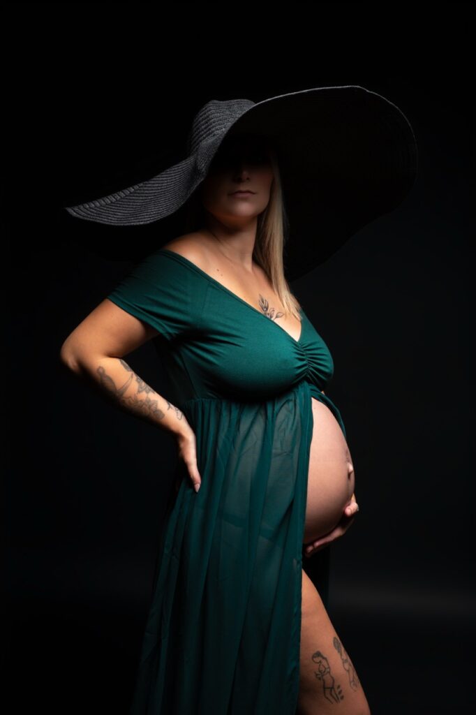 Future maman en robe verte et chapeau, séance grossesse en studio