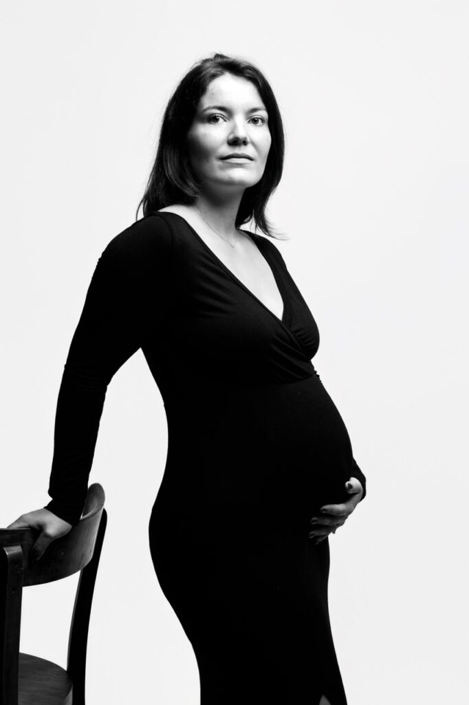 Future maman en robe noire sur fond blanc