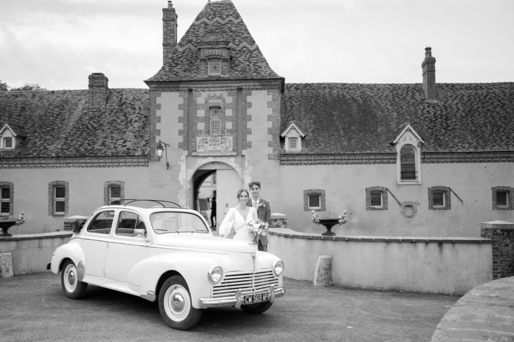 Voiture ancienne des mariés devant un château, noir et blanc