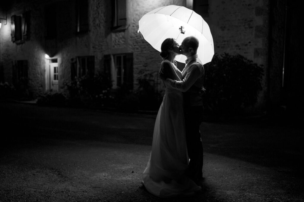 Les mariés sous un parapluie la nuit, noir et blanc