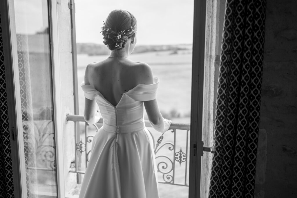 Mariée de dos face au balcon, robe épaules dénudées