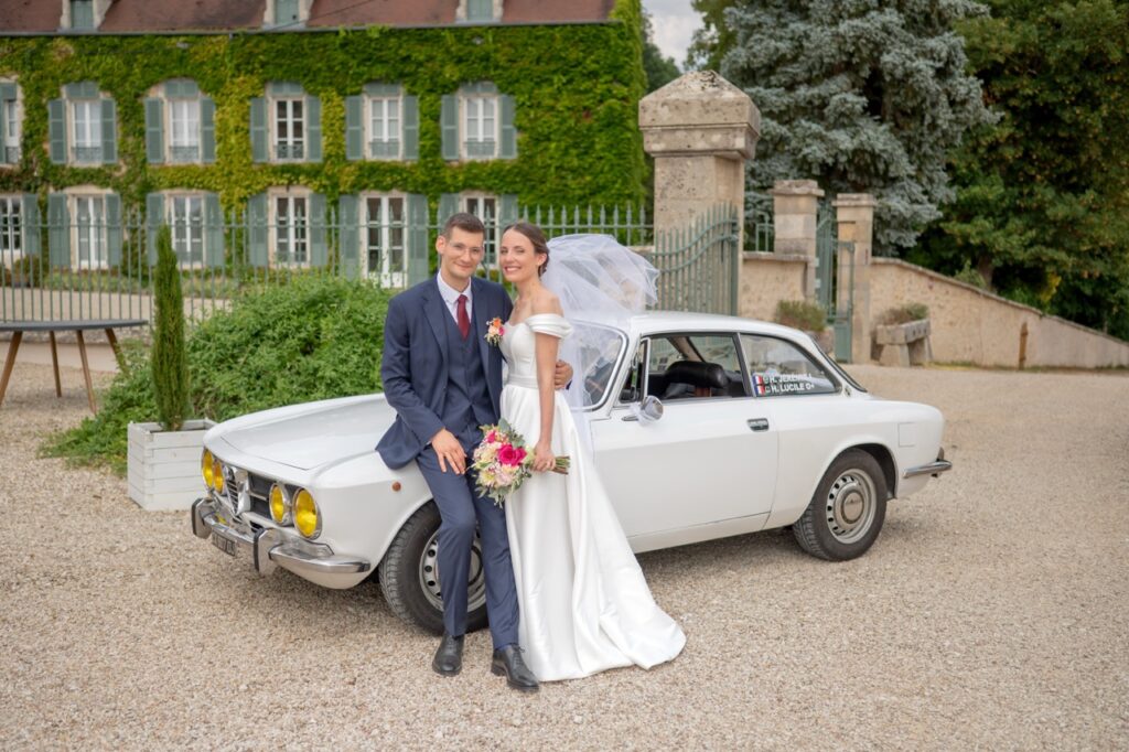 Les mariés sur une voiture ancienne devant un château